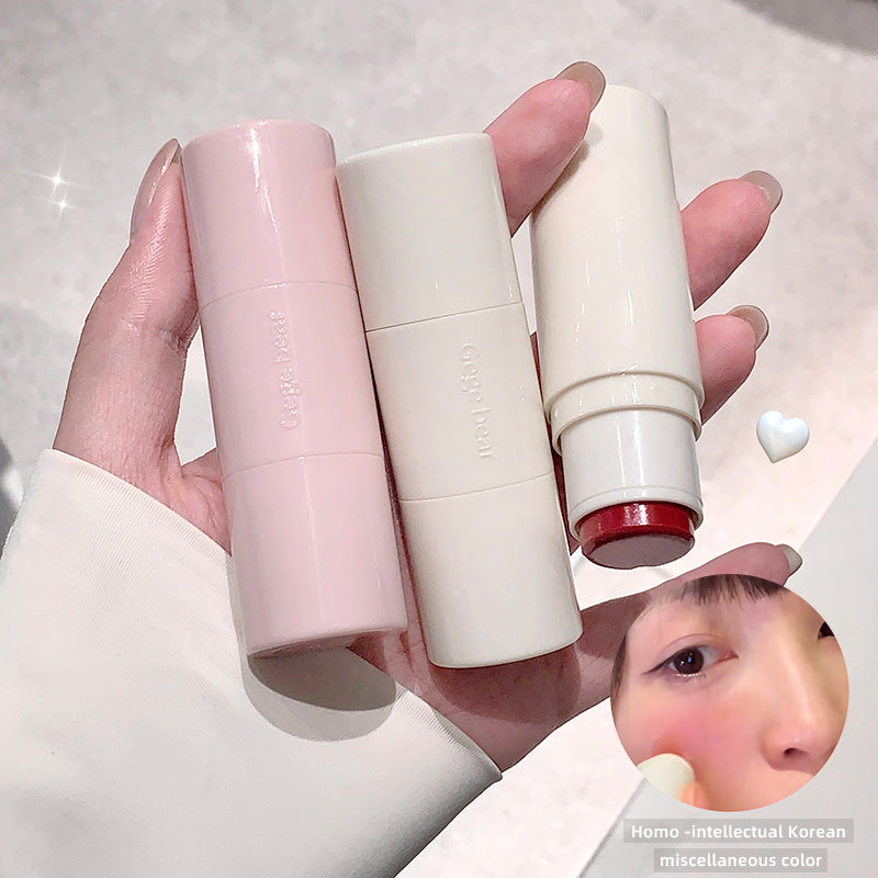 Three lipsticks in pink, white, and red held by a hand against a light background.
