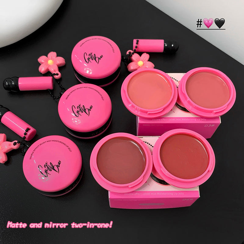 Pink makeup products with a mirror and applicator on a black surface