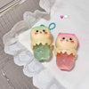 Two cute, cartoon-style hand sanitizers with a lace doily and tiled background.