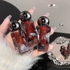 Three small bottles with a reflective surface held by a hand against a blurred background.