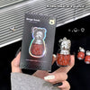 Bear-shaped lip gloss with packaging held by a hand, against a dark background.