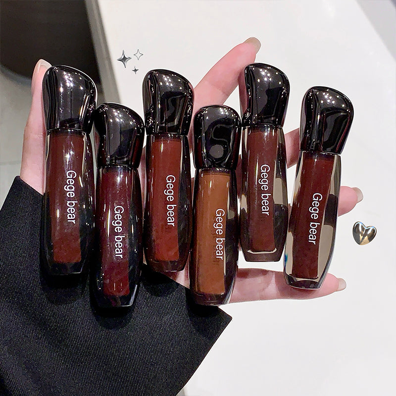 Hand holding six Gege bear lip glosses with a blurred background