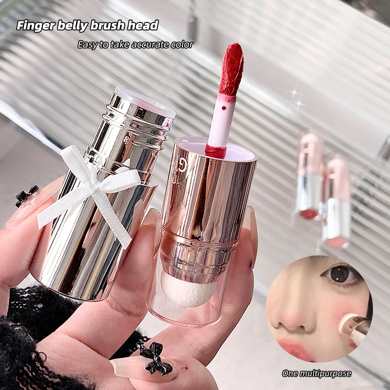 Lipstick with a brush head held by a hand, with text indicating its use for makeup application.