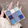 Makeup palette with blue and silver shades held by a hand