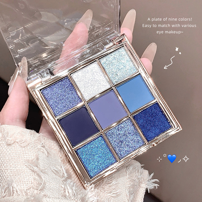 Makeup palette with blue and silver shades held by a hand