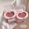 Two heart-shaped blushes in open cases held in a hand with a neutral background.