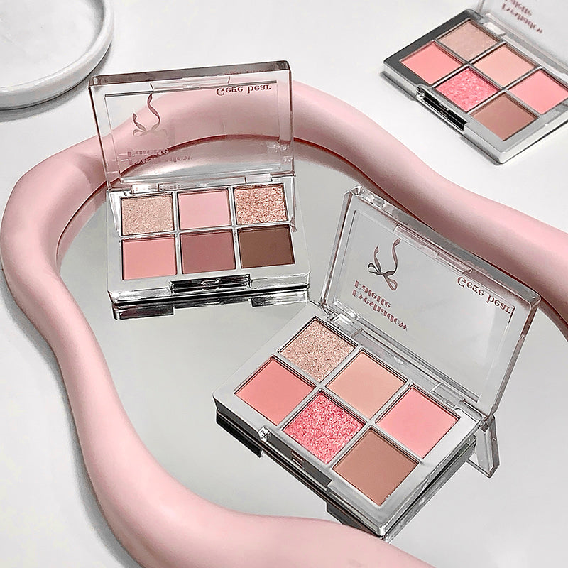 Makeup palettes with pink and brown shades on a white surface