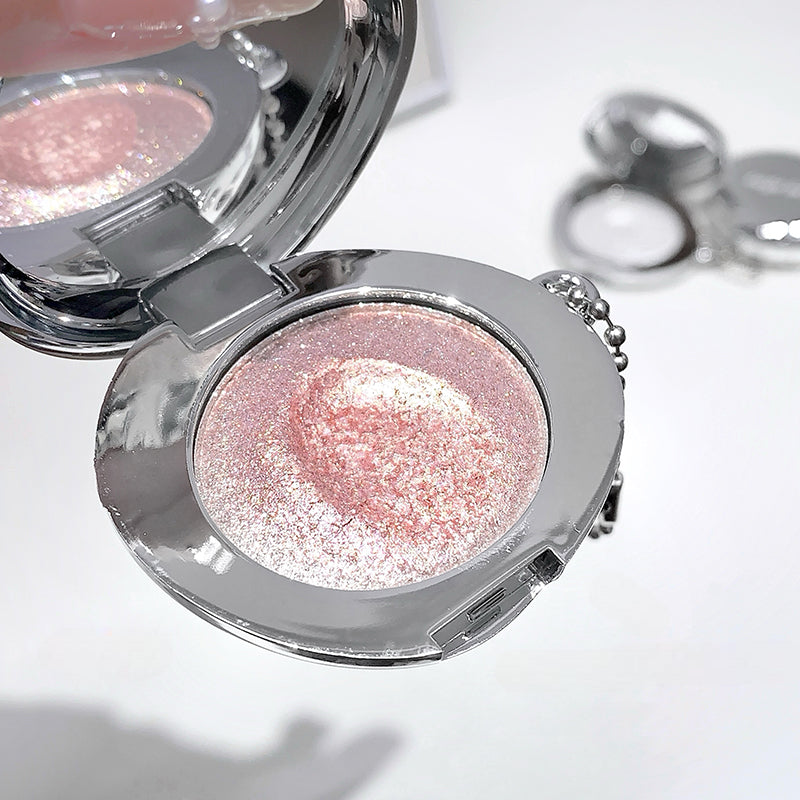 Compact mirror with pink glittery powder on a white background