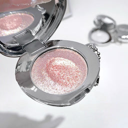 Compact mirror with pink glittery powder on a white background