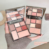 Two open eyeshadow palettes with a variety of colors held by a hand.