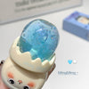 Cute character-shaped blue glittery object with cartoon face on a light background