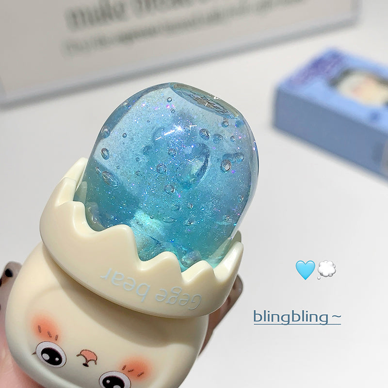 Cute character-shaped blue glittery object with cartoon face on a light background