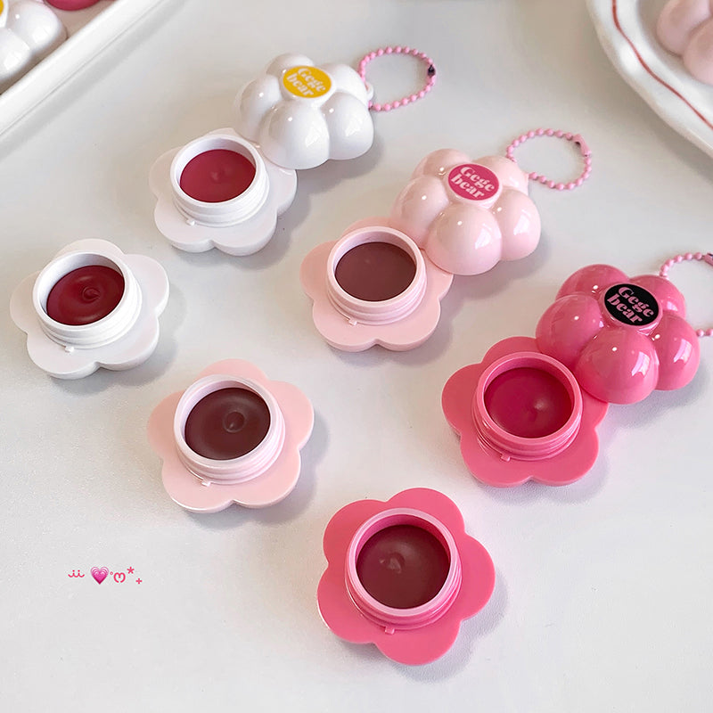 Flower-shaped lip balms in various colors on a white surface