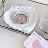 Makeup compact with a pinkish powder on a white dish, with 'Gee bear' packaging in the background.