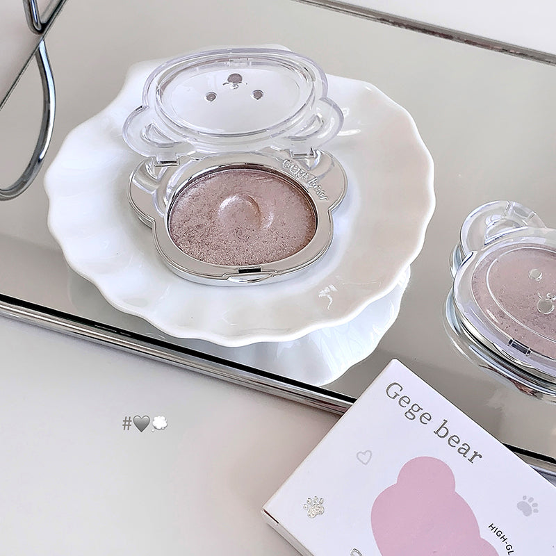 Makeup compact with a pinkish powder on a white dish, with 'Gee bear' packaging in the background.