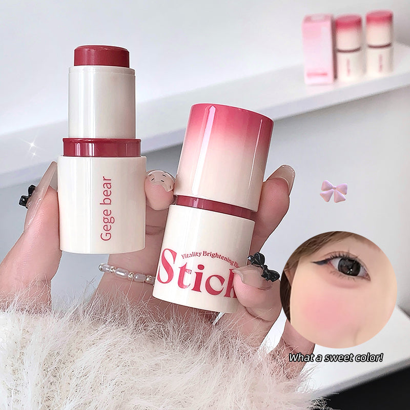 Two cosmetic sticks with pink and white design held by a person, with a blurred face in the foreground.