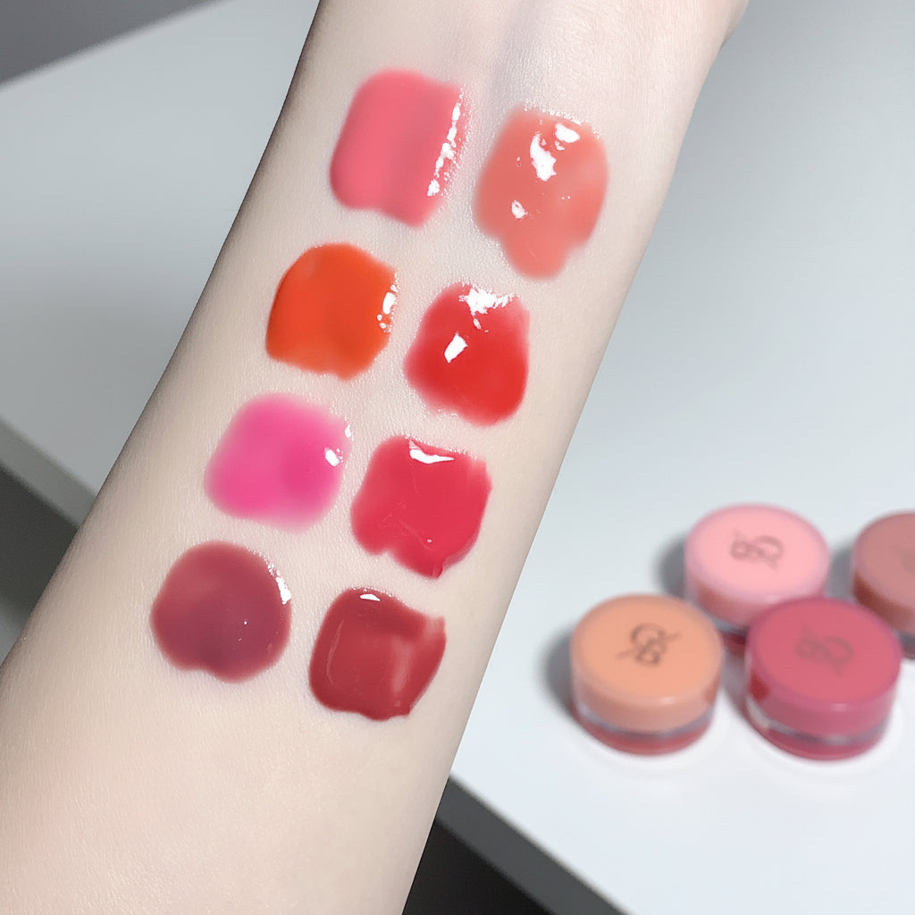 Lipstick swatches on a person's arm with lipsticks in the background.