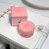 Pink cosmetic jar with lid and packaging on a white surface