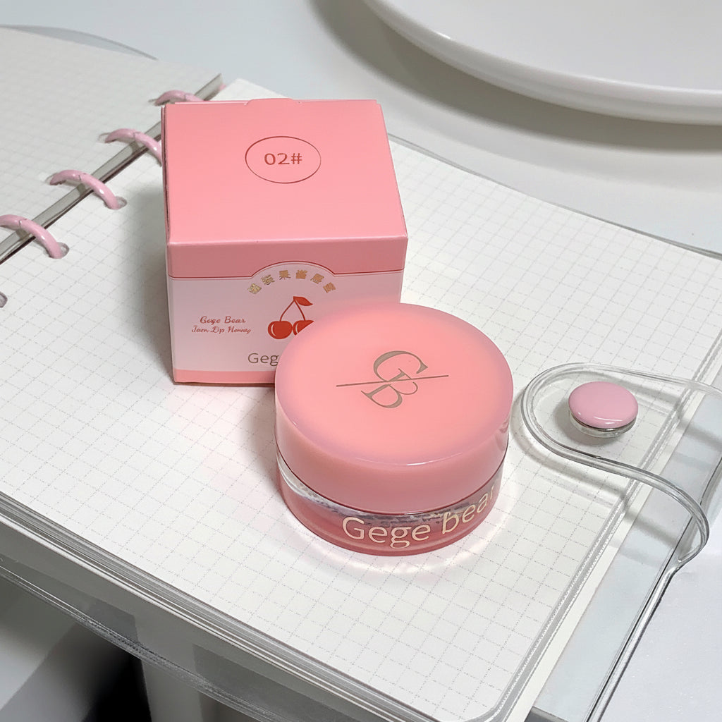 Pink cosmetic jar with lid and packaging on a white surface