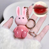 Pink bunny-shaped keychain held by a hand with a close-up of red lips inset.