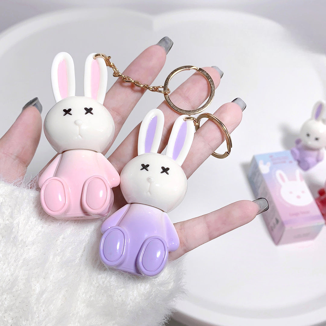 Two cartoon rabbit keychains held by a hand with a white background