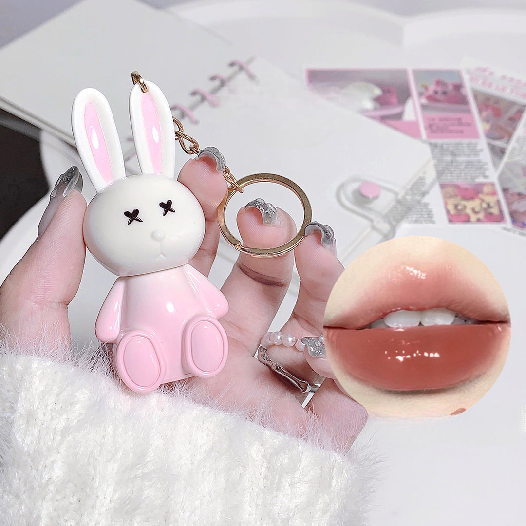 Pink bunny keychain held by a hand with a close-up of lips in the corner.