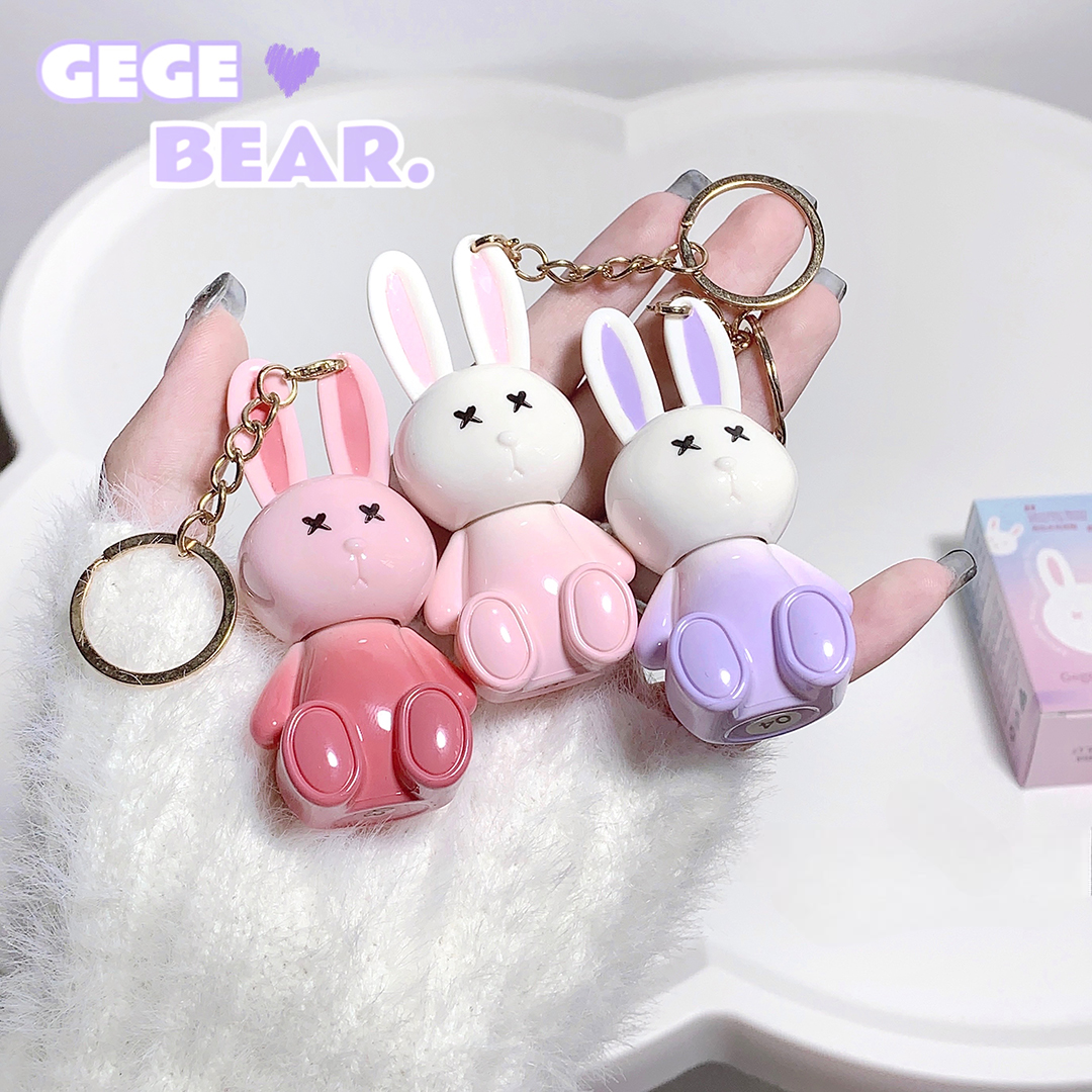 Three rabbit-shaped keychains in pink, white, and purple held by a hand on a white background with 'GEGE BEAR.' branding.