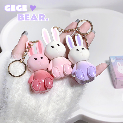 Three rabbit-shaped keychains in pink, white, and purple held by a hand on a white background with 'GEGE BEAR.' branding.