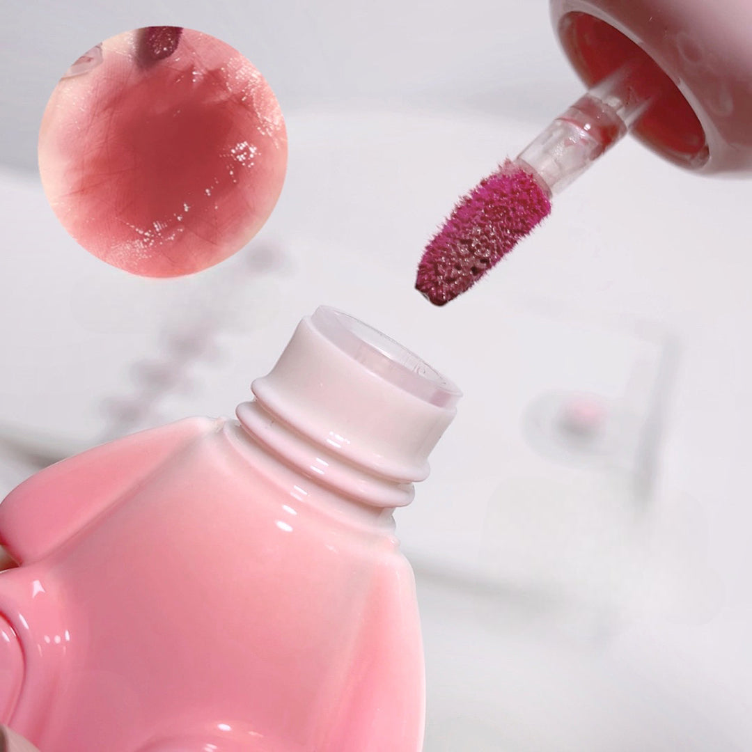Pink lip gloss being applied with a applicator on a white background