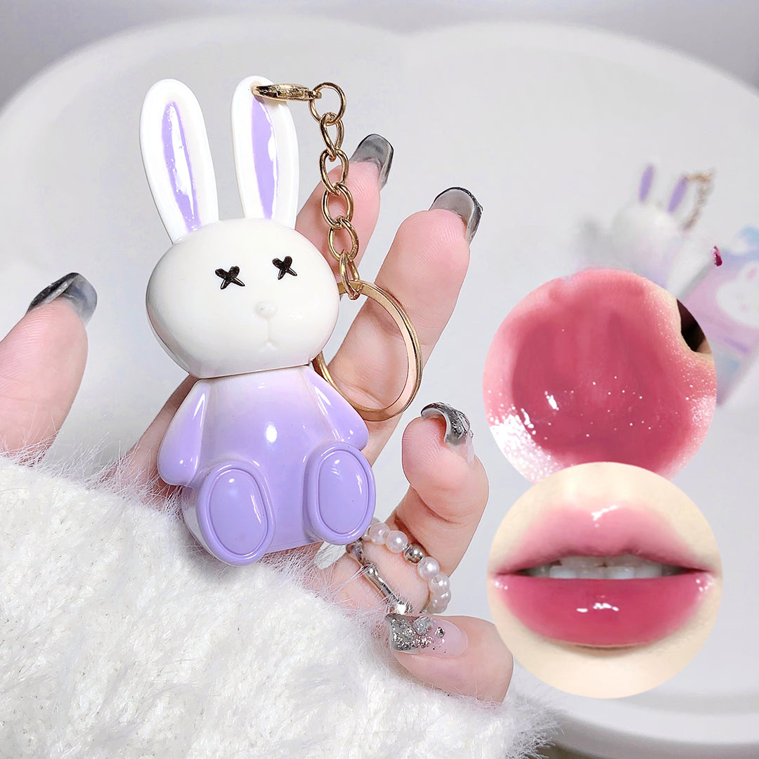 Keychain shaped like a cartoon bunny held by a hand, with close-up insets of pink lip gloss and a mouth.