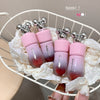 Pink gradient lip balm tubes with silver tops on a white chair.