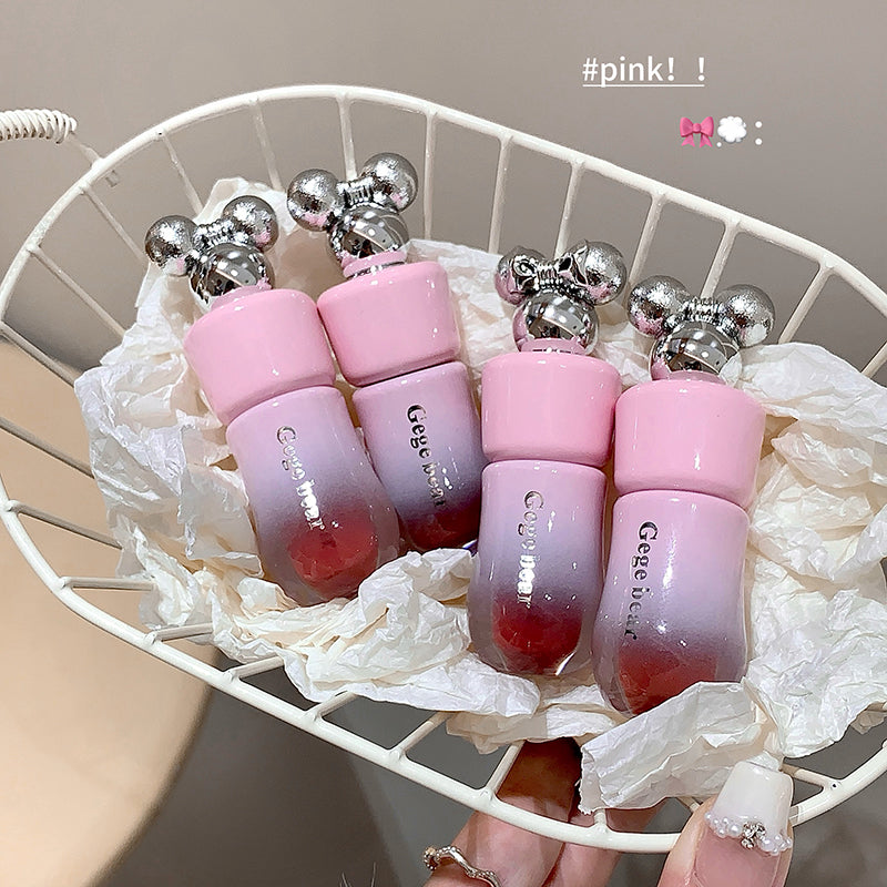 Pink gradient lip balm tubes with silver tops on a white chair.