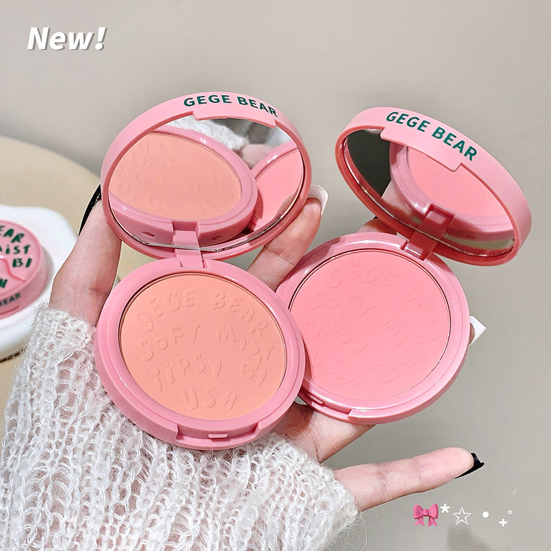 Two pink blush compactes with 'GEGE BEAR' branding held by a hand.
