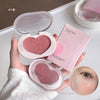 Heart-shaped blush compact with packaging held by a hand, on a neutral background.