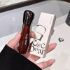 Hand holding a Gege Bear lip gloss and its packaging against a neutral background