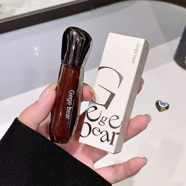 Hand holding a Gege Bear lip gloss and its packaging against a neutral background
