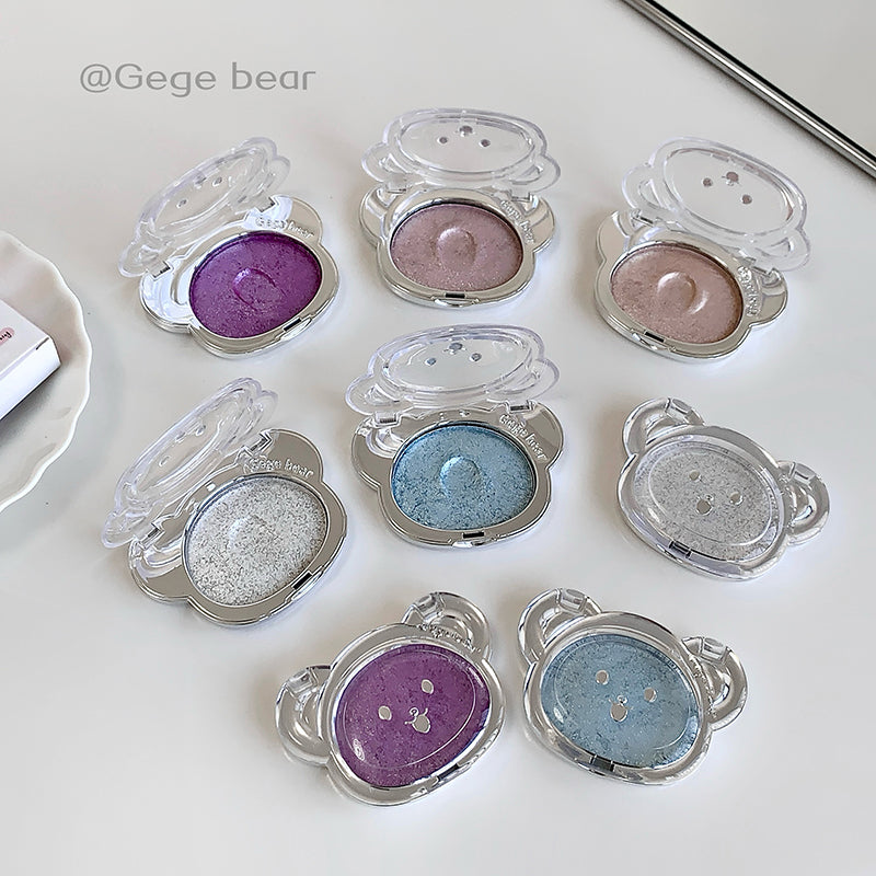 Multiple compact mirrors with colorful contents on a white surface, branded 'Gege bear'.