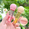 Two small glass bottles with colorful caps held by a hand against a green leafy background.