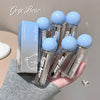 Set of Gege Bear lip balms with blue caps held in a hand against a neutral background.