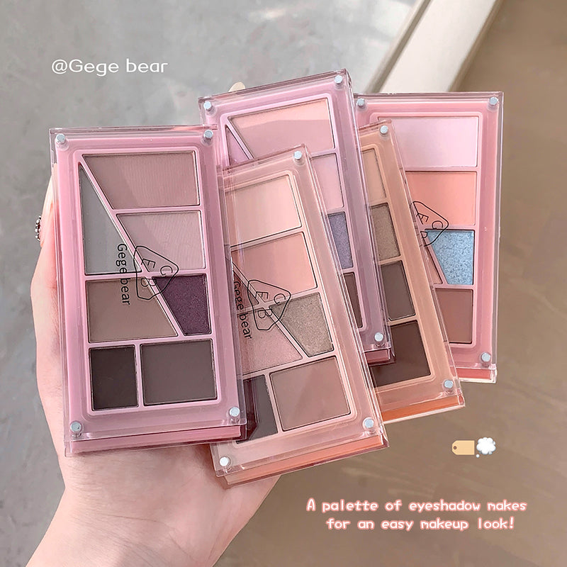 Makeup eyeshadow palettes with pink cases held by a hand