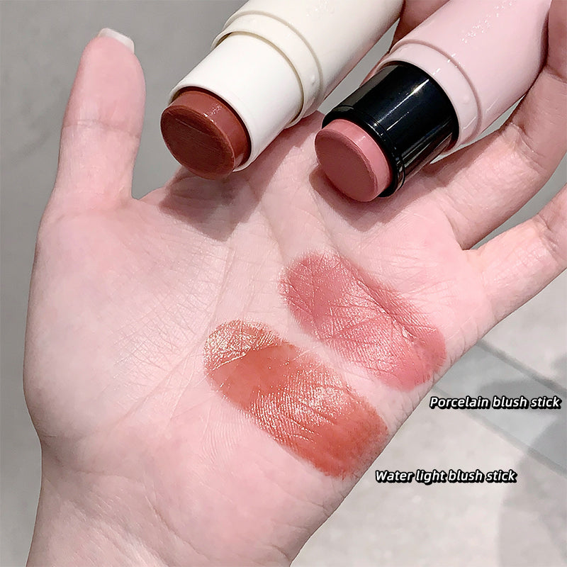 Two blush sticks with swatches on a hand