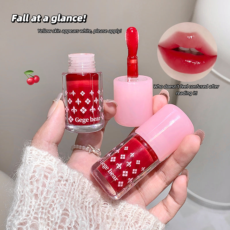 Hand holding two small red nail polishes with pink caps, labeled 'Gege bear', against a neutral background.