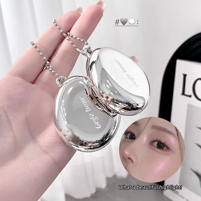Silver compact mirror held in a hand with a close-up of a face and text overlay.