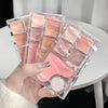 Makeup palette with pink shades held by a hand on a white surface