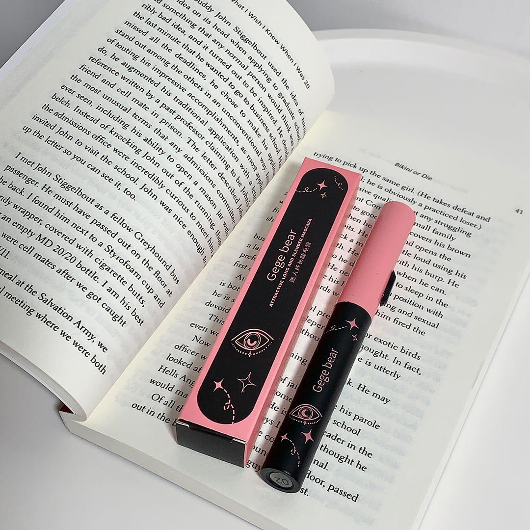 Two pink and black pens with a visible brand logo on an open book.