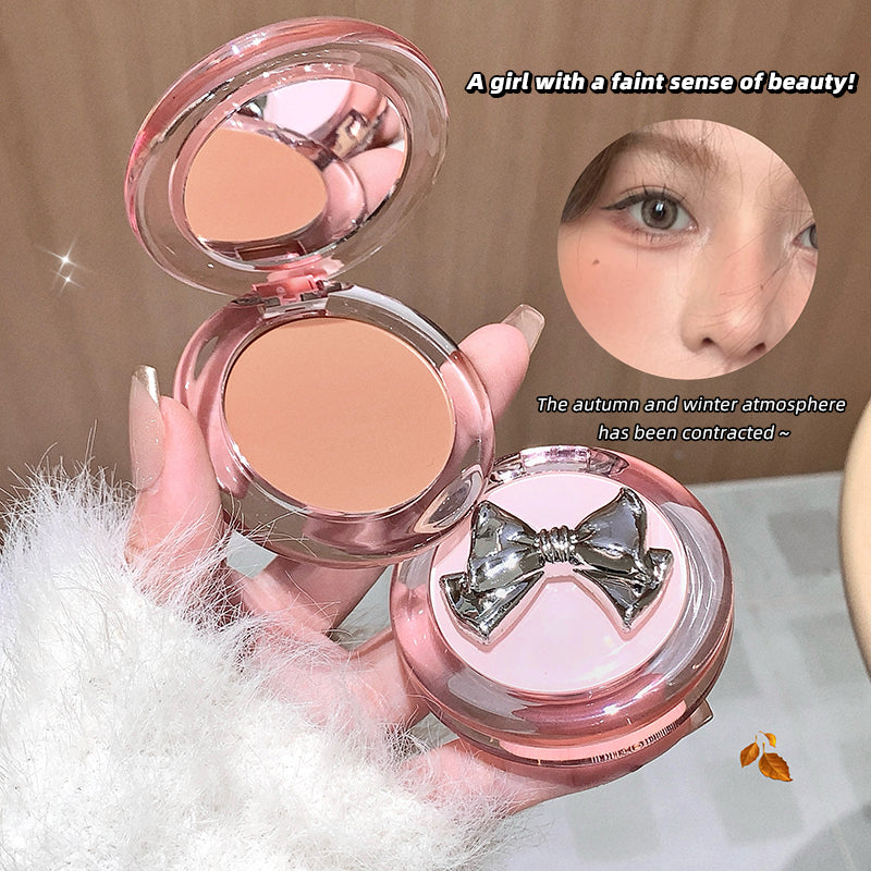 Compact powder with a decorative bow on a fluffy white surface