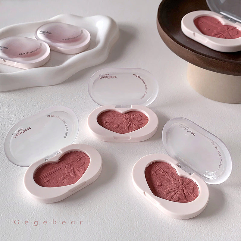 Heart-shaped blush compact with pink blush on a light gray background