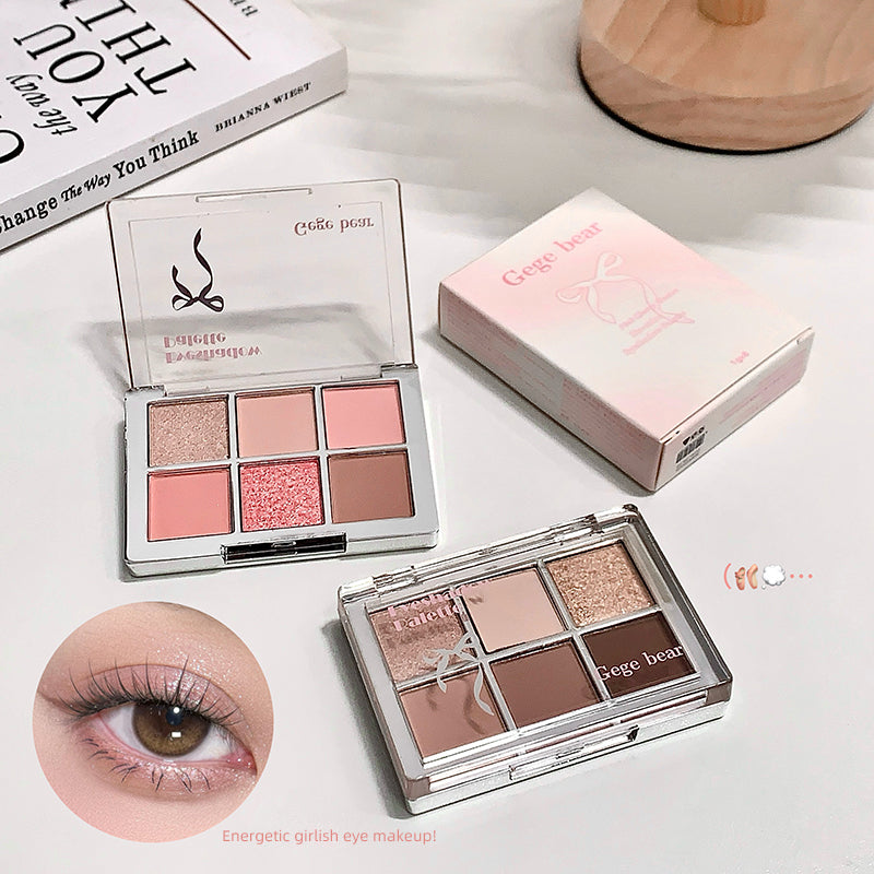 Makeup palette with eyeshadow shades and a close-up of an eye wearing pink makeup.