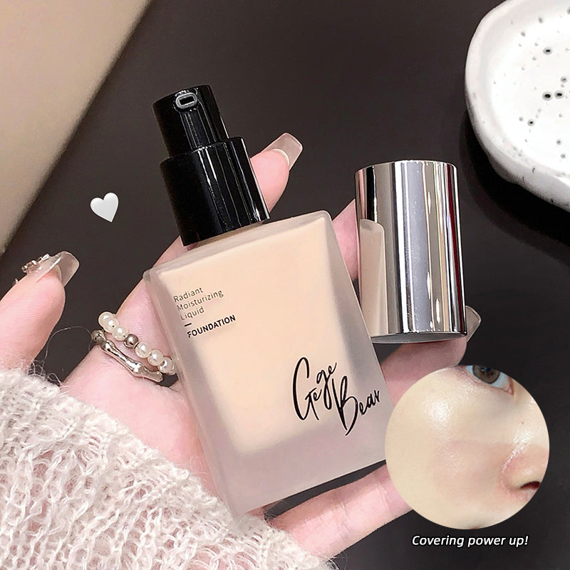 Foundation bottle held by a hand with a blurred background