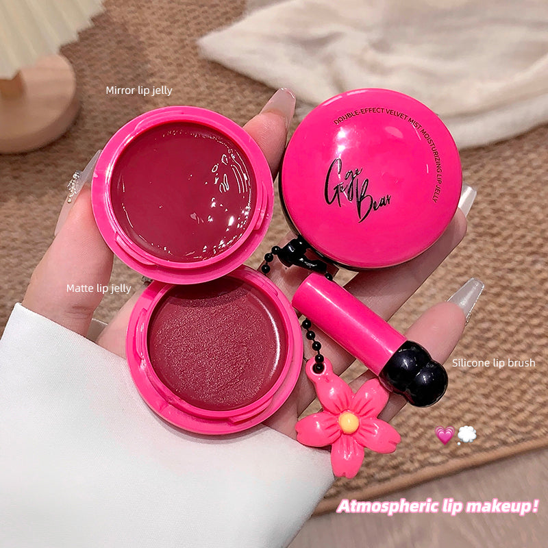 Pink makeup set with mirror, lip jelly, brush, and flower charm held by a hand.